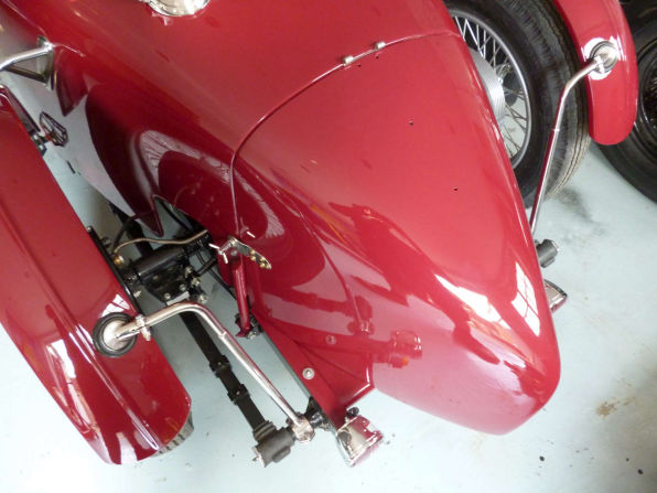A painted front cycle wing and its stay, with the front suspension and brake behind.