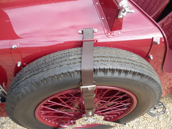 The spare wire wheel strapped to the rear of the body with a leather strap.